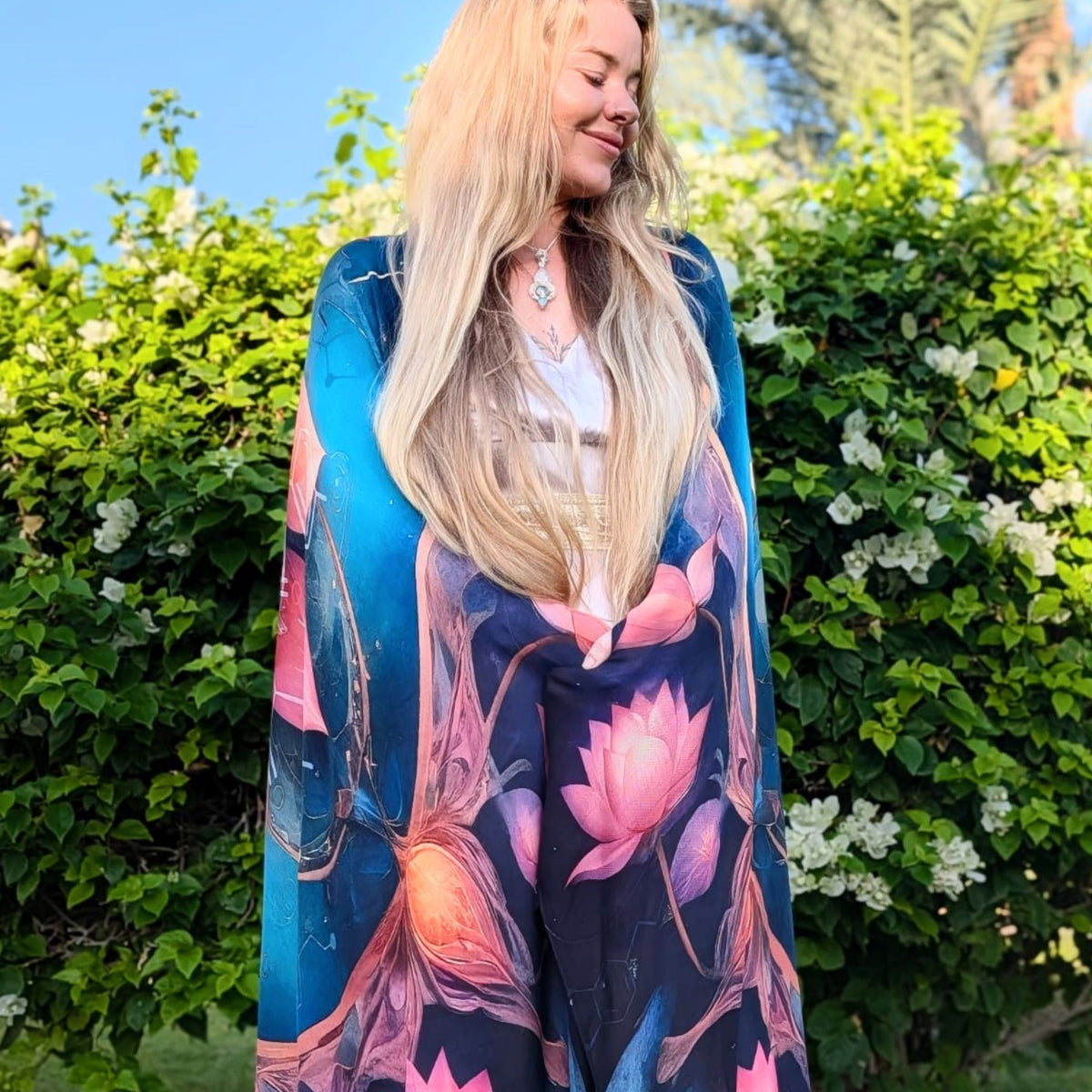 Calm Shawl worn as a full-length wrap in a flowering garden, navy blue with pink lotus design