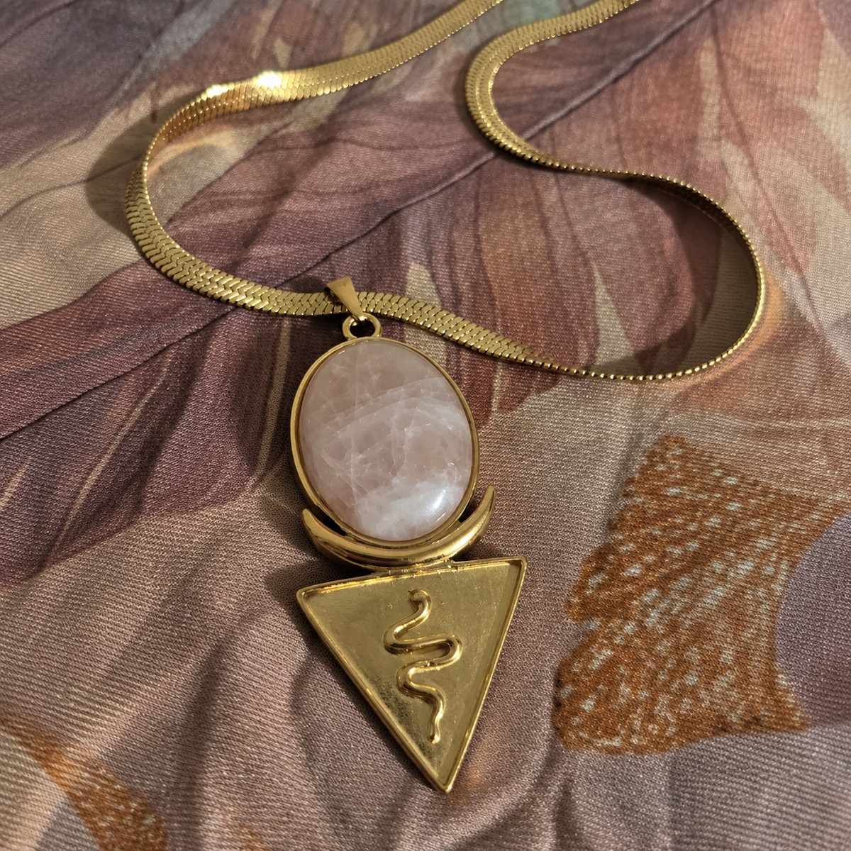 Rose quartz priestess necklace on a thick gold snake chain laid on a vegan silk shawl
