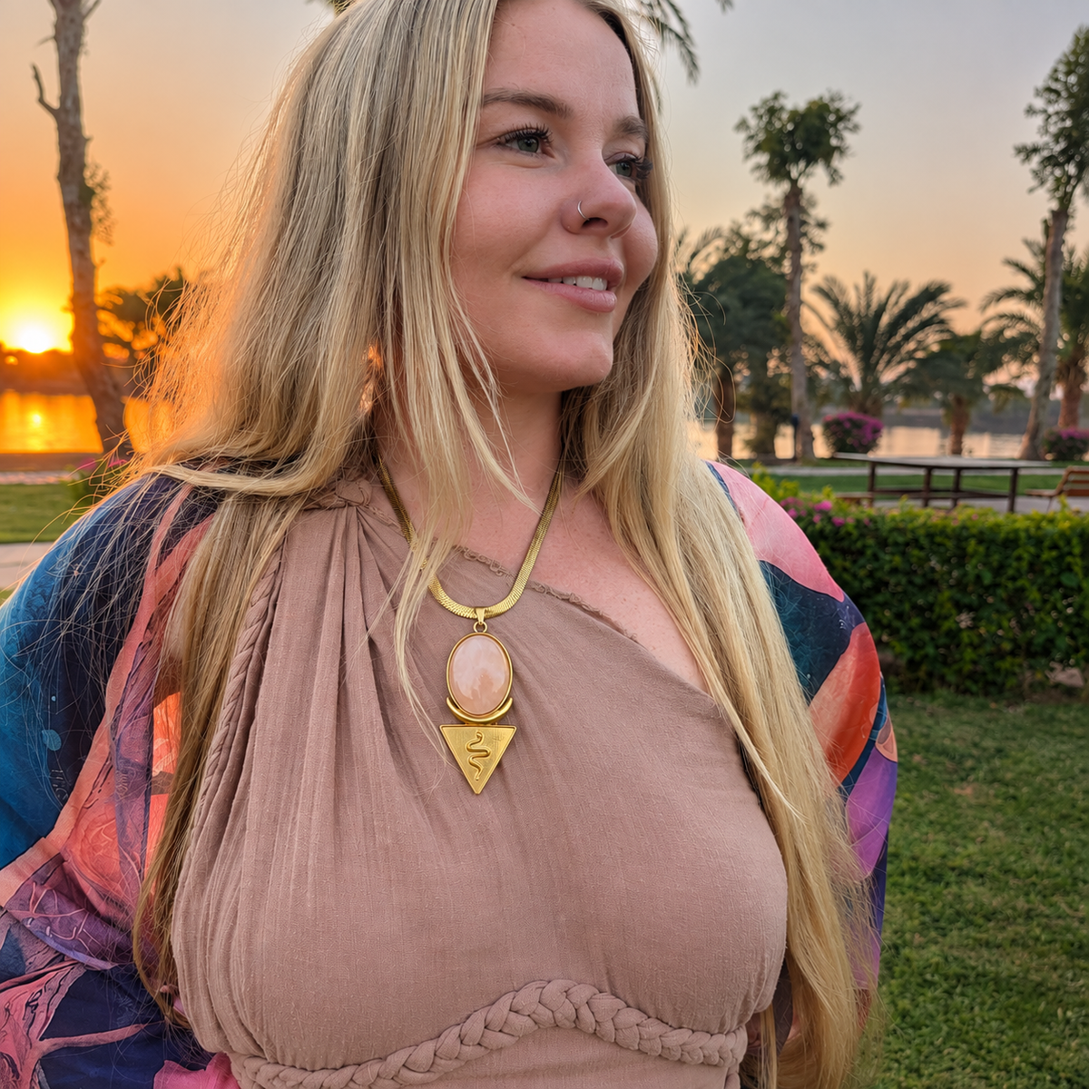 Woman at sunset among palm trees wearing the rose quartz snake crescent priestess necklace
