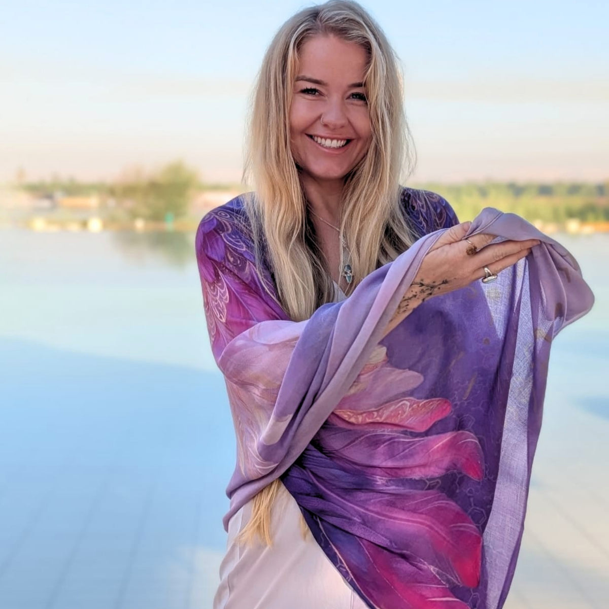 Woman wrapped in the Happiness Shawl purple and pink angel wing vegan silk wrap by the water