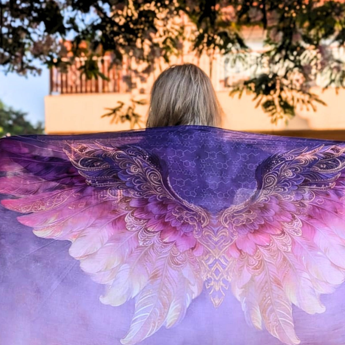 Back view of the Happiness Shawl purple, pink and gold angel wings spread open at sunset