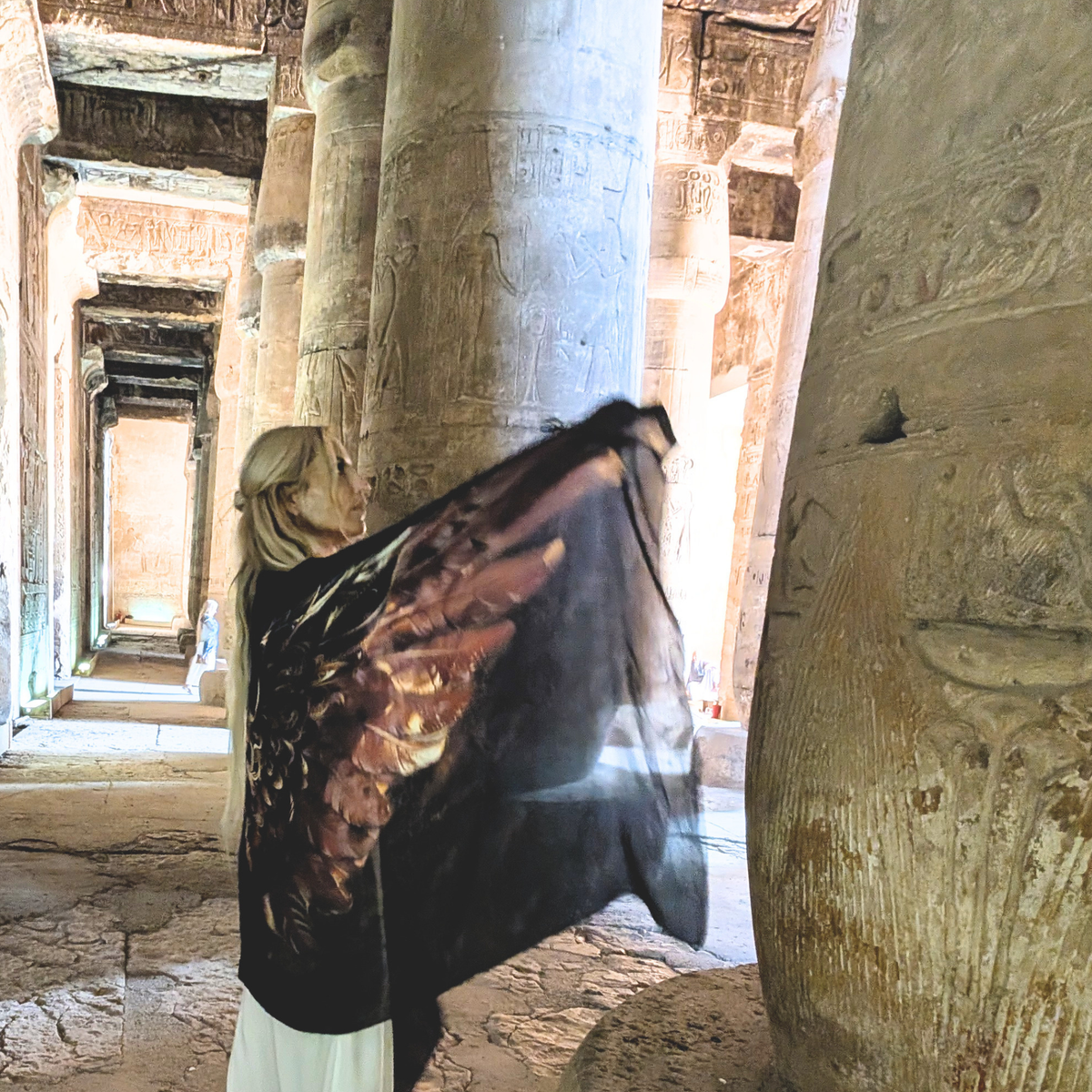 Strength Shawl brown and gold angel wings held open beside carved temple columns in Egypt