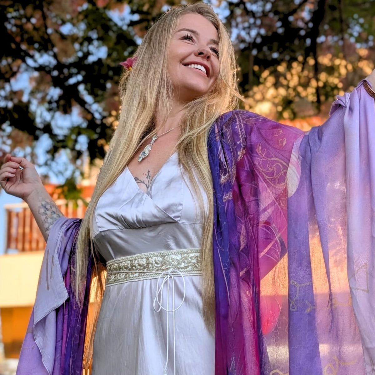 Joyful woman wearing the Happiness Shawl purple angel wing kimono over a silver satin dress