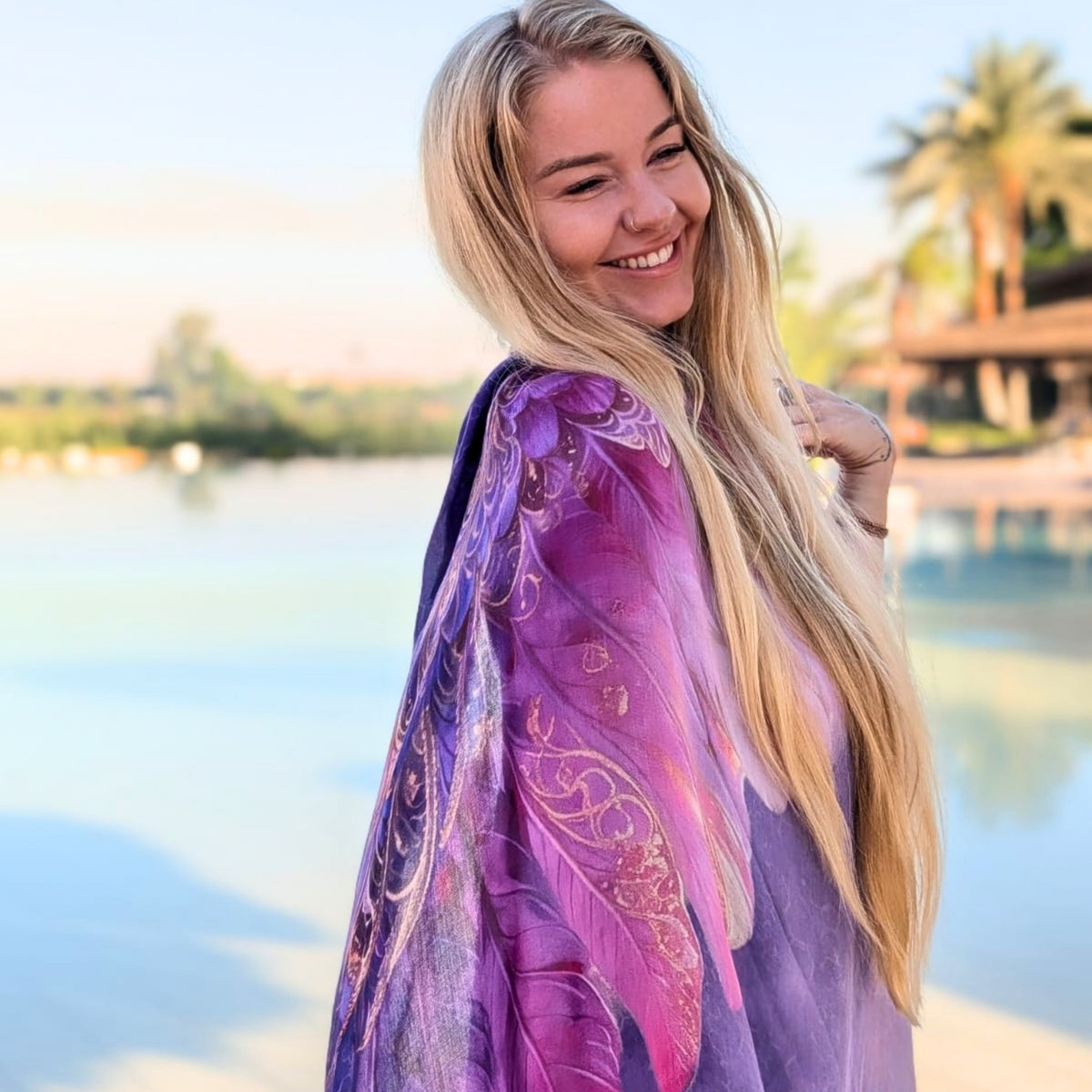 Smiling woman wearing the Happiness Shawl purple and pink angel wing wrap by the river