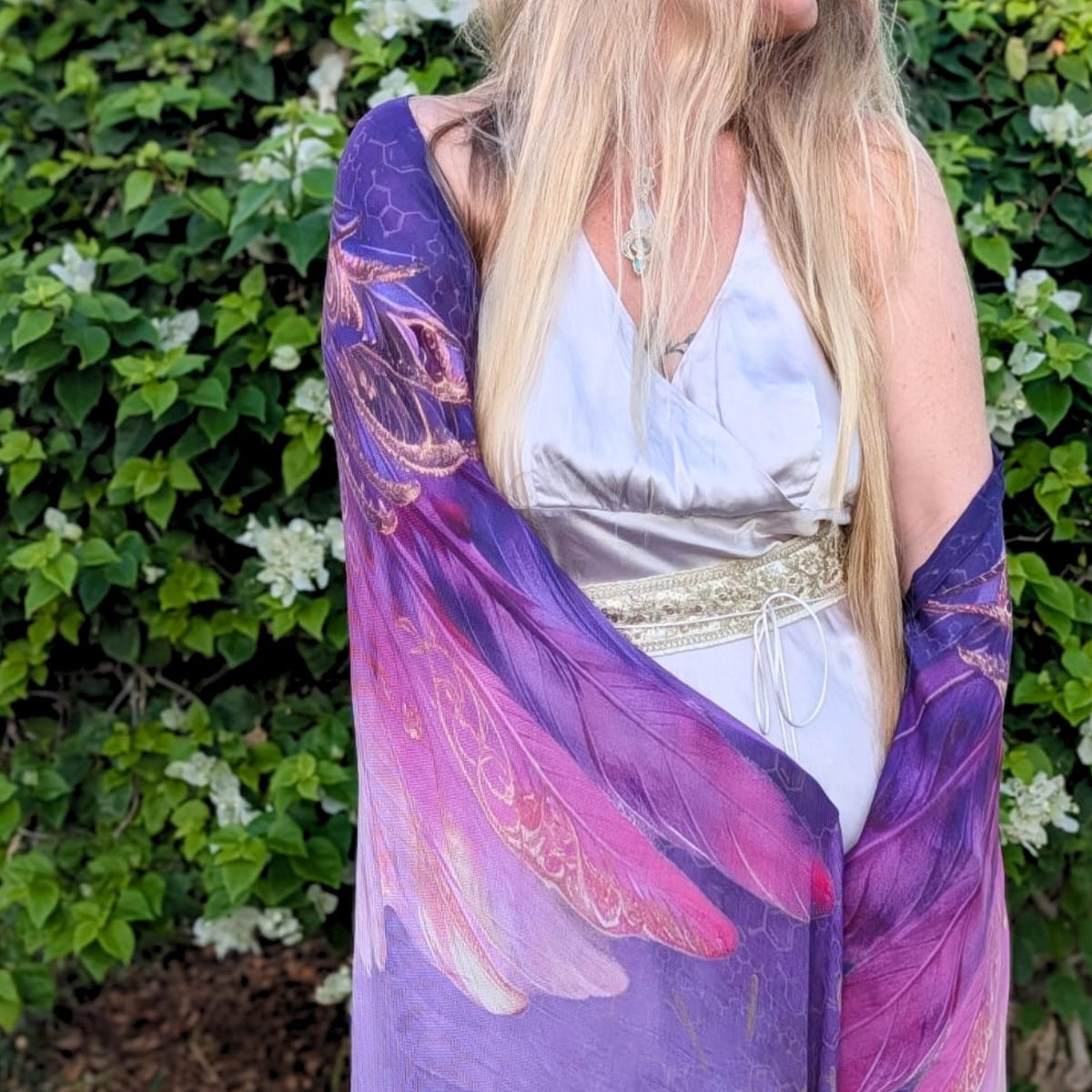 Happiness Shawl purple and pink angel wing wrap worn over a silver satin dress in the garden