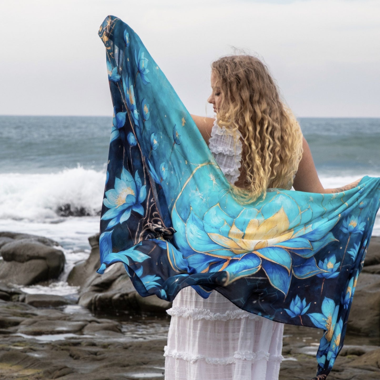 Woman wearing the Blue Lotus Intuition Shawl as bohemian festival wear, a lotus artwork festival scarf
