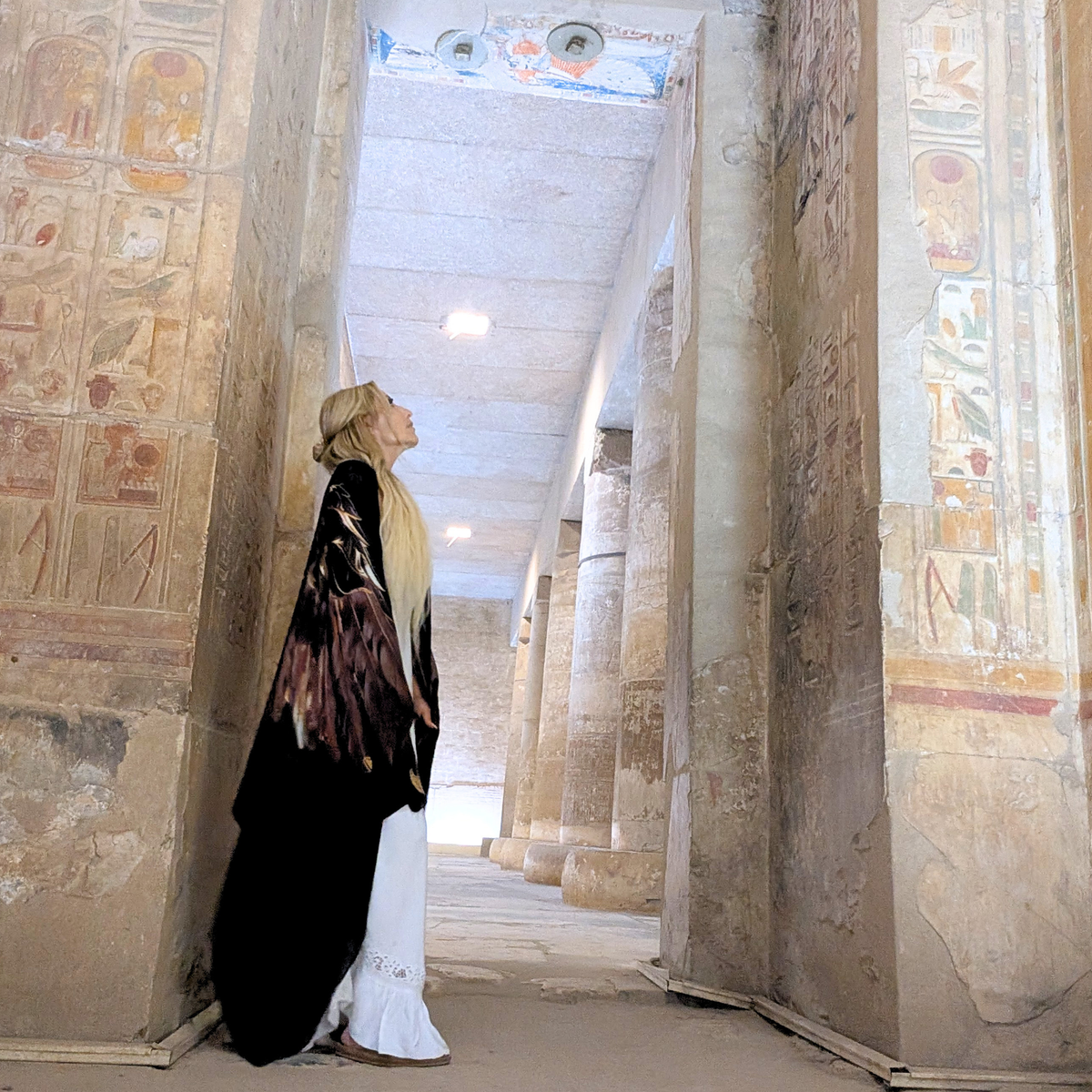 Woman wearing the Strength Shawl brown and gold angel wing kaftan in an ancient Egyptian temple